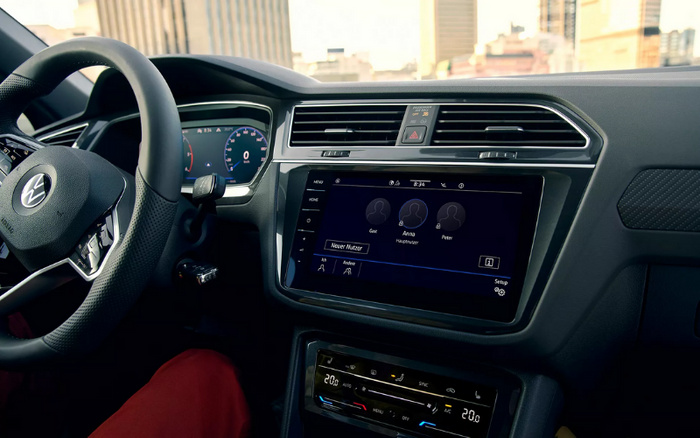 Interior view of a Volkswagen car dashboard featuring a steering wheel with the VW logo, digital speedometer showing zero, and a central touchscreen display with a user interface showing profiles named 'Gast', 'Anna Hauptnutzer', and 'Peter'. The screen also displays the time as 8:34 and options such as 'Neuer Nutzer', 'Setup', and home and menu buttons. Below the touchscreen is the climate control panel set to 20.0 degrees Celsius. This modern car interior highlights features relevant to both used cars and new cars buyers.