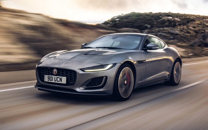 Silver Jaguar F-Type sports car with registration plate 901 UCN driving fast on a winding road through a mountainous area under a cloudy sky, showcasing sleek design and modern headlights, ideal for buyers looking for used cars or new cars.